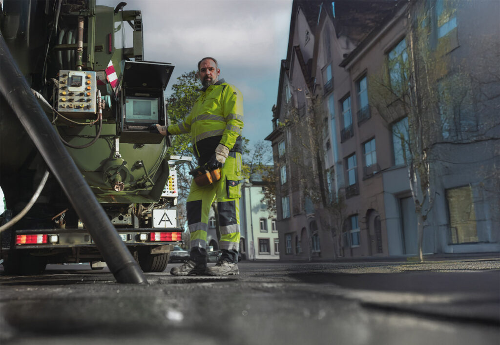Mitarbeiter von Meyer Entsorgung bedient moderne Kanalreinigungstechnik an einem Spezialfahrzeug im Einsatz auf einer Stadtstraße
