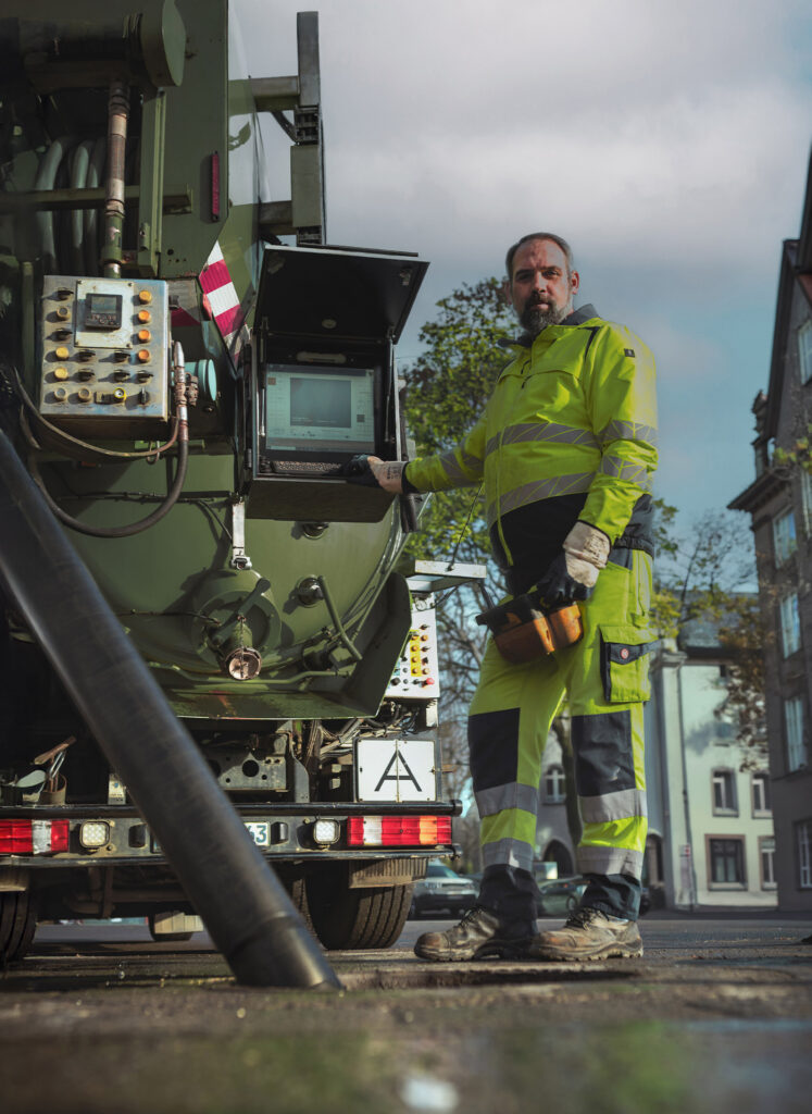 Mitarbeiter von Meyer Entsorgung bedient moderne Kanalreinigungstechnik an einem Spezialfahrzeug im Einsatz auf einer Stadtstraße